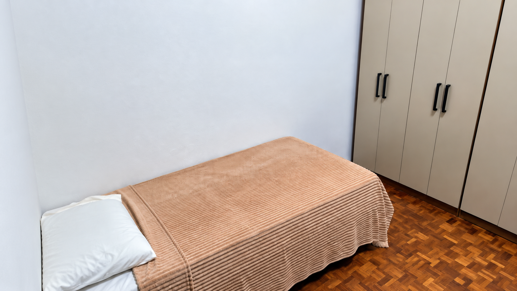 Quarto da Tenerezza, com cama, armário e piso de madeira.
