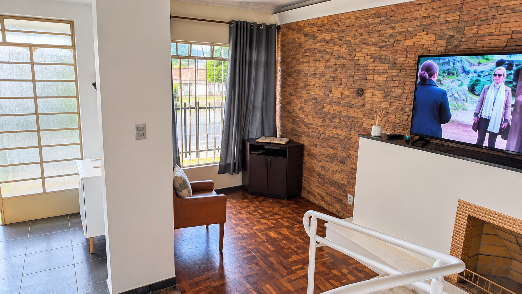 Sala de convivência da Tenerezza, com poltronas, televisão e lareira.