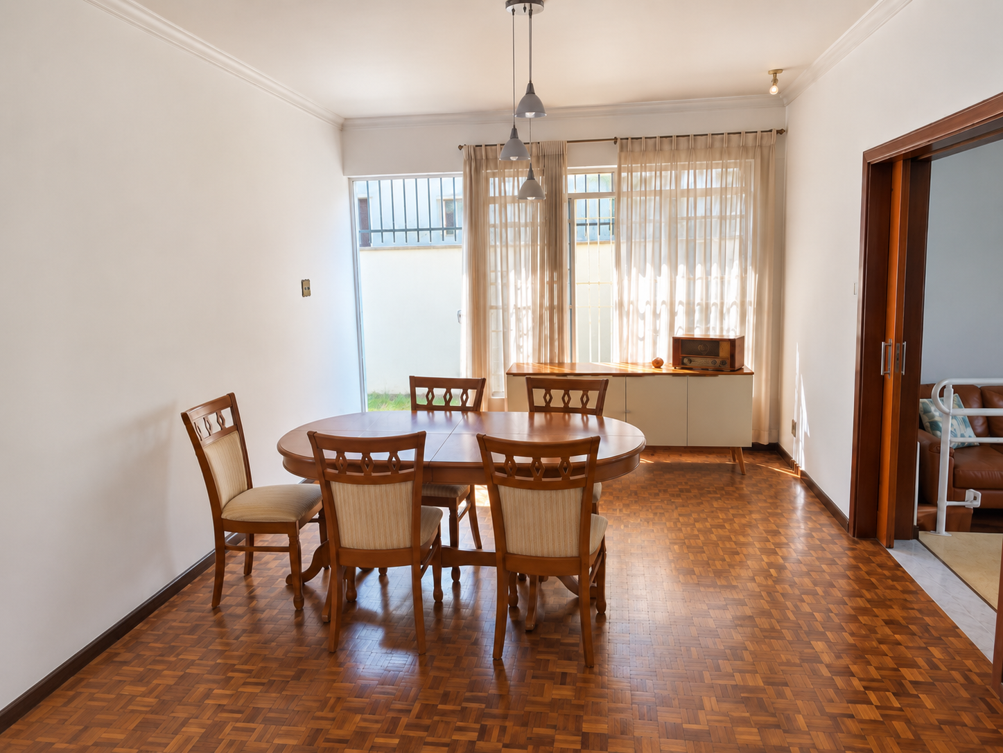 Sala de refeições da Tenerezza, com mesa e cadeiras de madeira junto à janela.